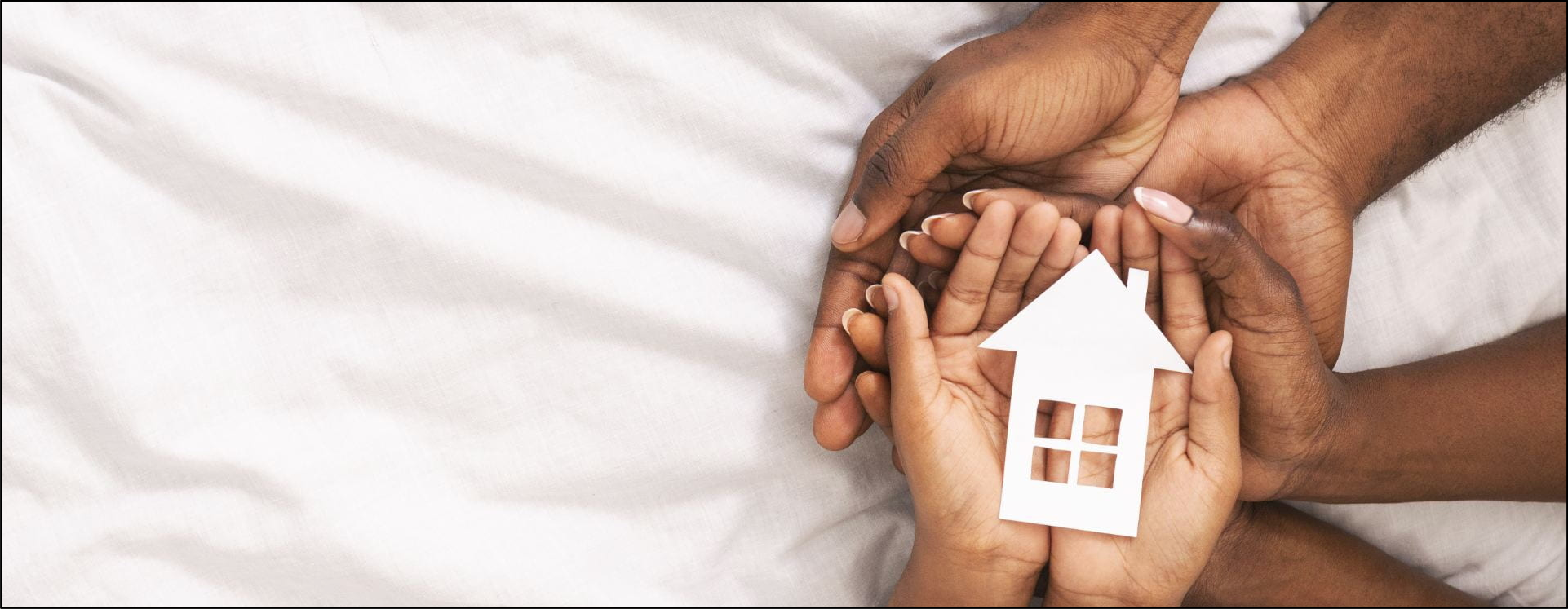 Hands holding a paper cut out of a home
